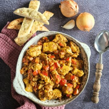 Een kom romige kip kerrie met rijst. Ernaast naanbrood om de kip kerrie mee op te lepelen.