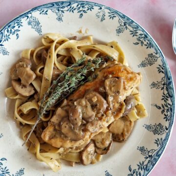 Een bord pasta met kip en champignonsaus.