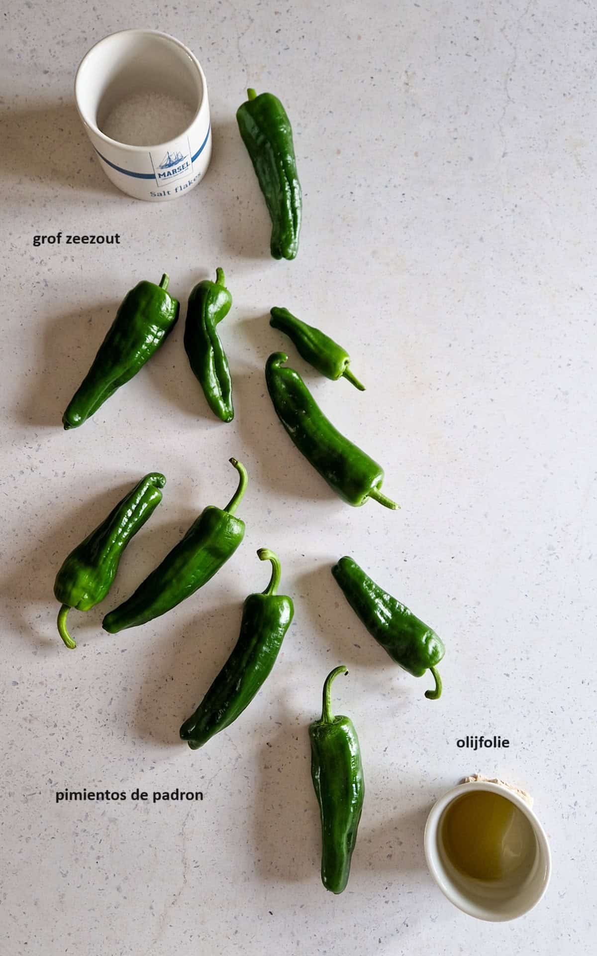 De ingredienten om Pimientos de Padron klaar te maken: Spaanse groene pepers, grof zeezout en olijfolie.