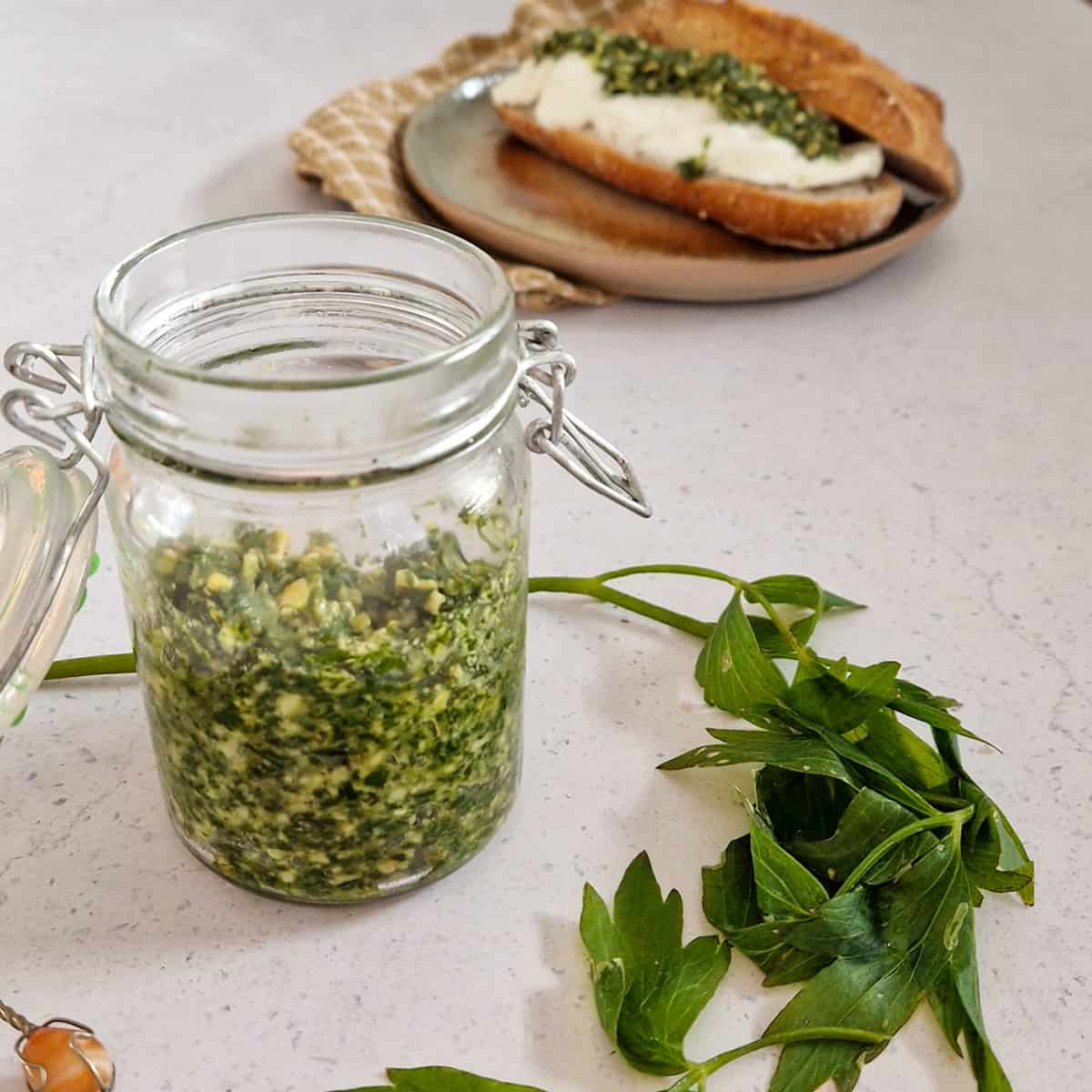 Een potje lavaspesto met lavasbladeren ervoor.