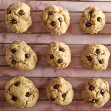 Pindakaaskoekjes zonder suiker met kleine chocolate chips die op een rekje liggen af te koelen.