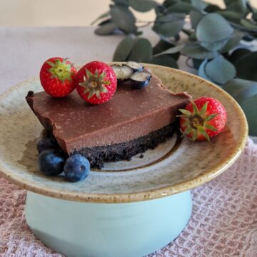 Een stukje Oreo ganachetaart op een taartbordje, gegarneerd met rood fruit.