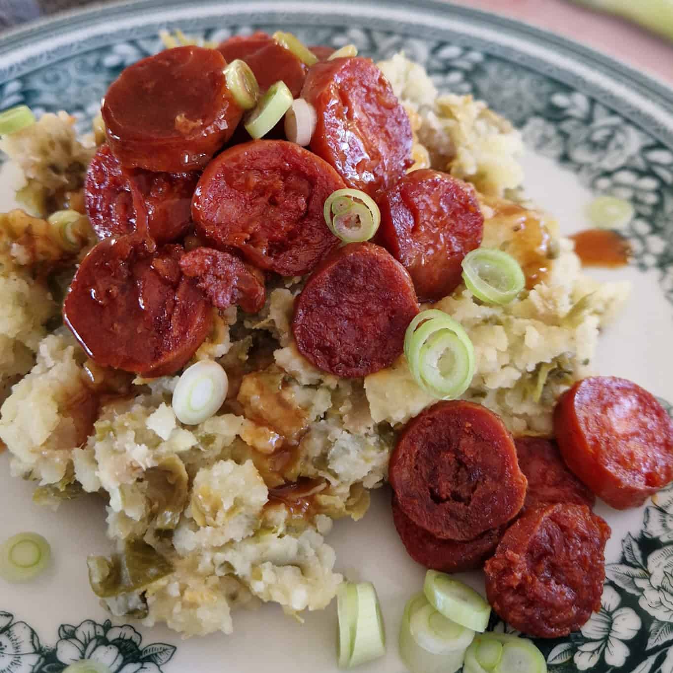Spruitjes stamppot met chorizo en bosui op een bord met ouderwets motief.