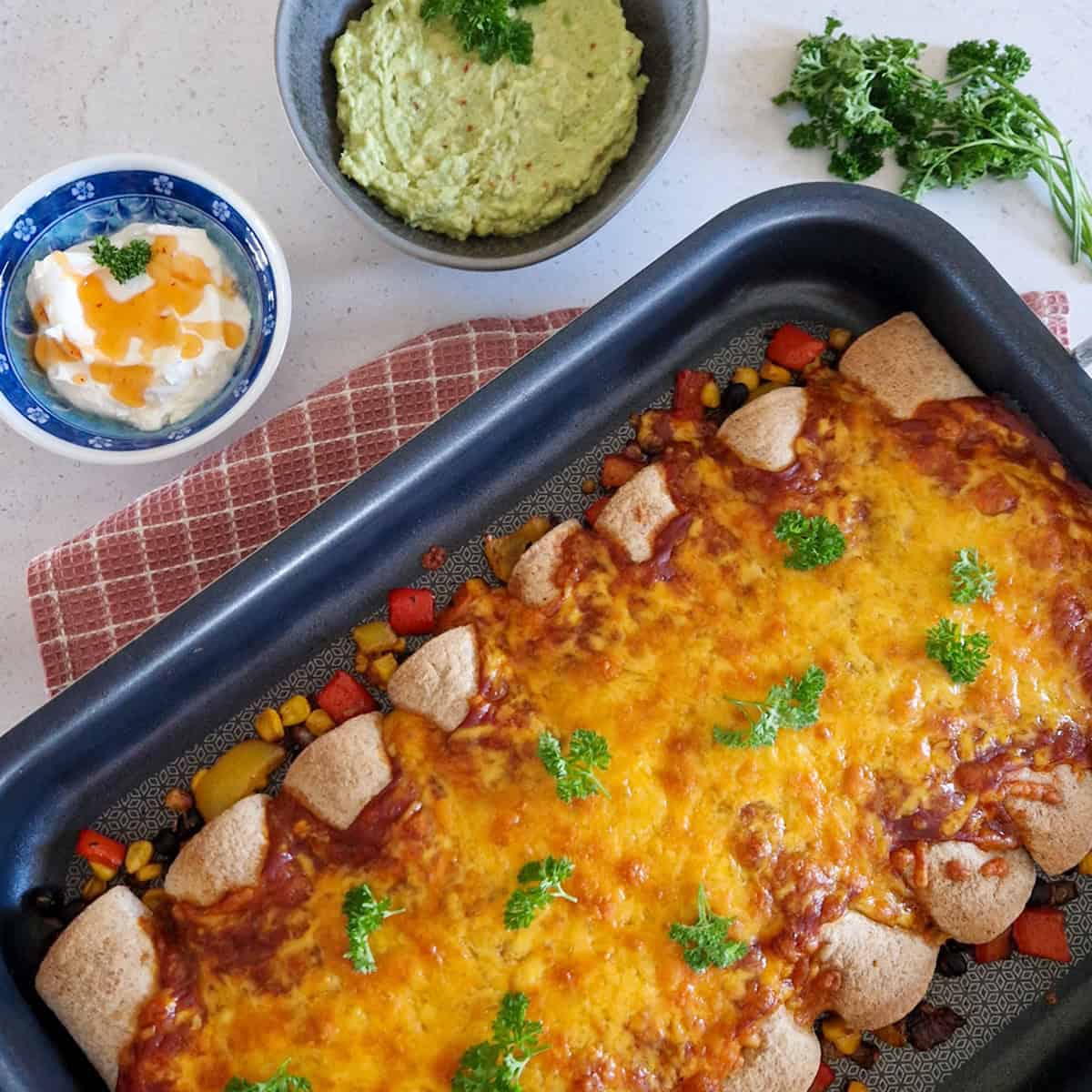 Een ovenschotel met vegetarische enchiladas met een royale laag gegratineerde cheddar.