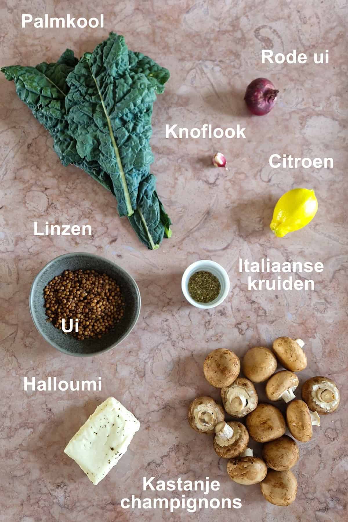 De ingrediënten voor palmkoolsalade, uitgestald op een bruine, marmeren ondergrond.
