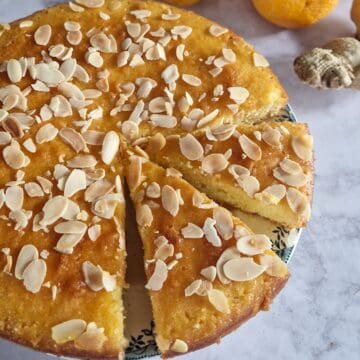 Een polentacake, gegarneerd met amandelschaafsel. Er zijn twee punten losgesneden van de cake.