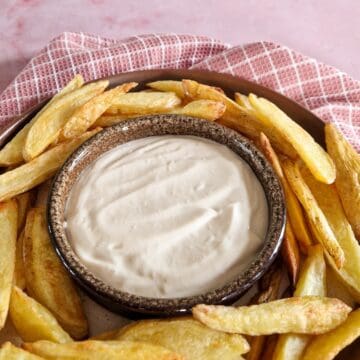 Een bakje zelfgemaakte mayonaise, met gebakken aardappels uit de oven er omheen.