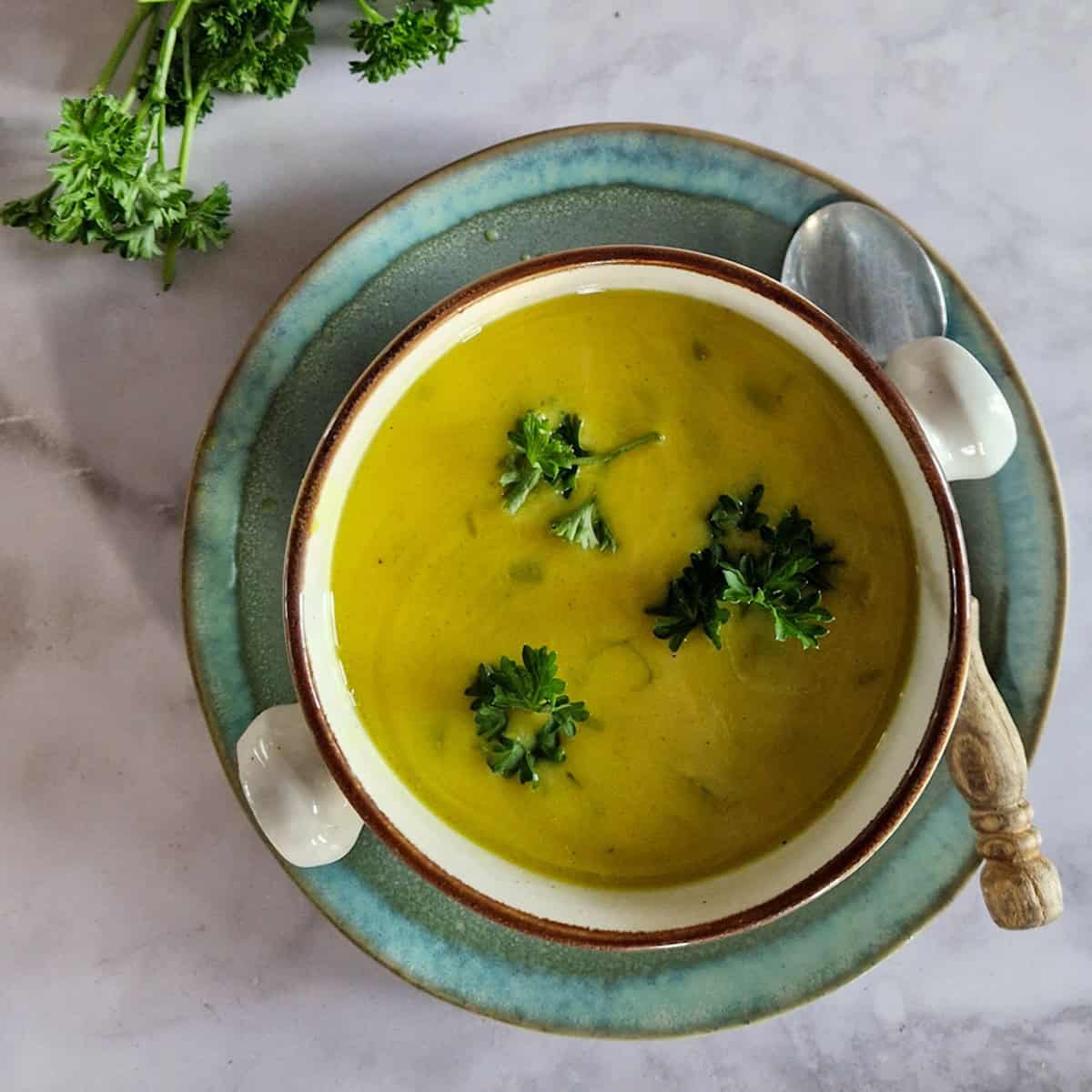 Een kom lichtgebonden, romige kerriesoep. De soep is gegarneerd met verse peterselie.