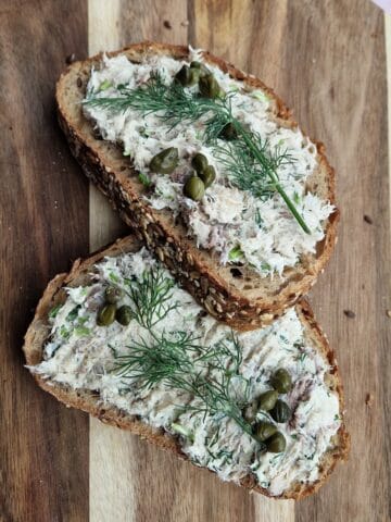 Twee boterhammen met zelfgemaakte makreelsalade, gegarneerd met verse dille en kappertjes.