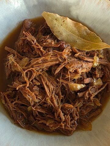 Een kom met ouderwets draadjesvlees. Het gerecht is gegarneerd met een laurierblaadje.