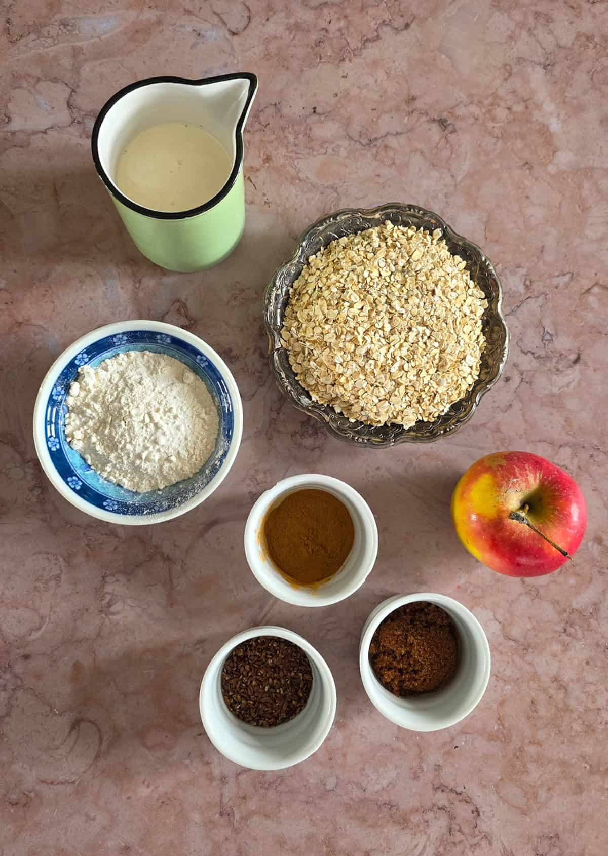 De ingrediënten voor het maken van appelwafels met havermout, uitgestald op een marmeren ondergrond.