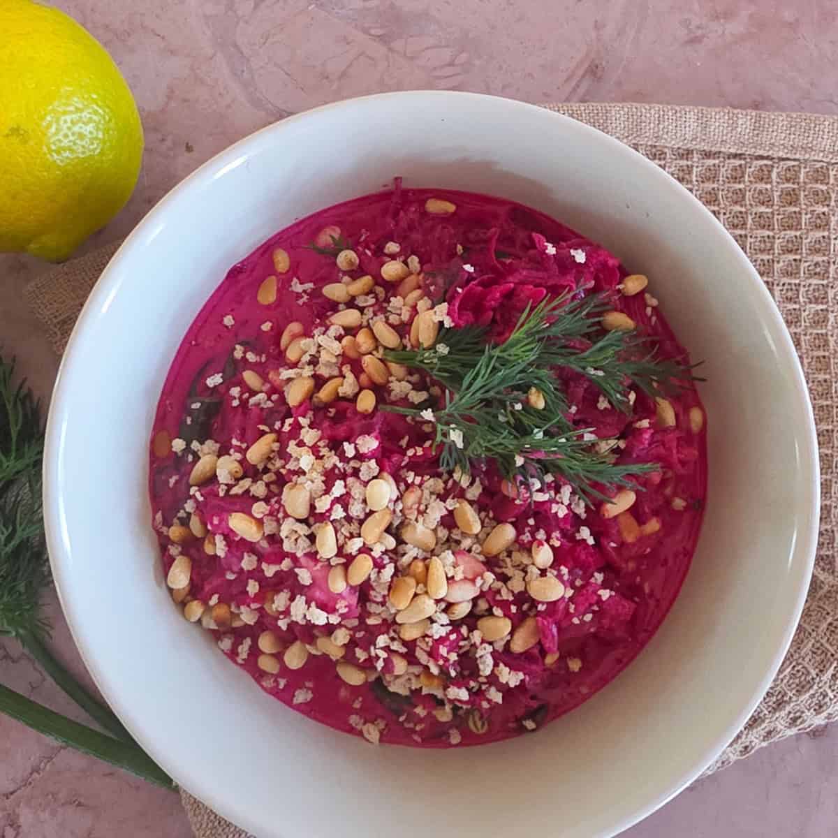 Een kom bieten orzo met pijnboompitten, panko en dille.